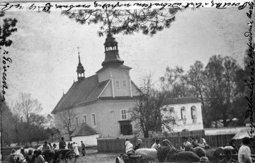 Fotografia czarno-biała. Grupa ludzi na tle kościoła.