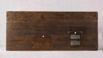 Stół z litego drewna, z prostokątnym blatem na wysokim oskrzynieniu- wtórnie przerobionym ( pierwotnie dwie szuflady pod blatem). 4 nogi graniaste zwężają sie nieznacznie do dołu. Mebel  wykonany z litego drewna sosnowego. Na blacie w częsci centralnej odciśnięty, wypalony kształt dłoni.