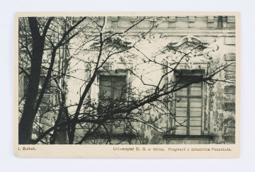 Pocztówka wykonana w sepii, przedstawia fragmnet Dziedzińca Poczobuta Uniwersytetu Stefana Batorego w Wilnie. Na pierwszym planie bezlistne drzewa, w tle ściana budynku z trzema oknami. Nad oknami słabo widoczne sztukaterie.
