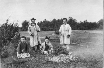 Fotografia czarno-biała przedstawia czterech chłopców przy ognisku.