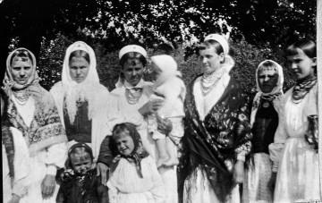 Fotografia czarno-biała przedstawia grupę kobiet i dzieci w strojach ludowych. 
