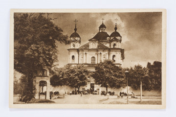 Pocztówka z widokiem na kościół św. św. Piotra i Pawła na Antokolu w Wilnie, wykonana w sepii. Na pierwszym planie pusty plac przed kościołem, w głębi malutkie, ciemne postacie ludzkie i kilka drzew. Po lewej stronie ułomek bramy. Nad placem góruje barokowa świątynia z trzema wieżami.