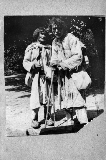 Fotografia czarno-biała przedstawia dwóch żebraków opierających się na lasce.