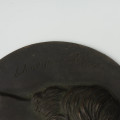 Medalion z wizerunkiem Klaudyny Potockiej - ujęcie 3/4; Fragment medalionu z widocznym tyłem głowy z włosami w puklach. Z lewej strony wygrawerowany napis Claudyna Potocka.