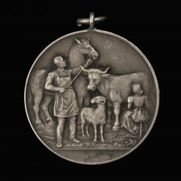 Medal nagrodowy Izby Rolniczej Prowincji Pomorze - rewers; Okrągły medal z kompozycją herbową i realistyczną, z uszkiem i koluszkiem. Na rewersie mężczyzna w fartuchu trzymający za uzdę konia, obok kobieta dojąca krowę, pośrodku stojący baran.