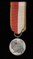 Medal 40-lecia Polski Ludowej - ujęcie z tyłu; Odznaka Medalu 40-lecia Polski Ludowej w postaci srebrzonego, oksydowanego krążka ze wstążką i przylutowanym uszkiem. Na rewersie medalu umieszczony jest wgłębiony kontur granic Polski, a w środku konturu napis w trzech wierszach: WALKA / PRACA / SOCJALIZM, pod napisem znajduje się gałązka oliwna. Wstążka medalu jest szerokości 32 mm, składająca się z dwóch pionowych pasków w środku w kolorze białym i czerwonym o szerokości 12 mm każdy i dwóch pasków po bokach o szerokości 4 mm koloru złotego. Wstążka zawieszona na kółku w formie rózg liktorskich o średn. 16 mm, przechodzącym przez uszko medalu.