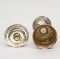Puchar Hartwiga - ujęcie z góry; Z prawej strony leżący srebrny puchar w formie kielicha. Stopa okrągła. Dolna część płaszcza stopy ozdobiona repusowanym ornamentem typu lambrekinowego.  Z lewej strony wnetrze pokrywy.