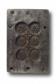 Jedna ze stron formy z negatywowym rytem przedstawiającym piernik Katarzynkę składający się z sześciu ozdobnych medalionów ustawionych parami w trzech rzędach. Płaska powierzchnia formy pokryta wzmacniającą metalową blaszką. 
