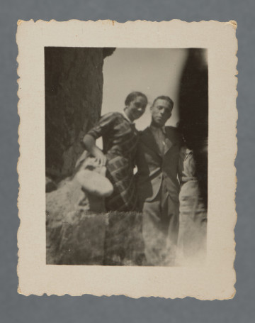 Fotografia przedstawia dwie kobiety i stojącego pomiędzy nimi mężczyznę w garniturze - Hilela Poznera. Kobieta po lewej ma białą torebkę, ubrana jest w kraciastą sukienkę (ta sama postać  - na kolejnym w kolekcji zdjęciu), kobieta po prawej ma twarz zasłoniętą przez niezidentyfikowany przedmiot lub element aparatu przypadkowo przesłaniający kadr, ubrana w jasną sukienkę. Nie wiemy, kim były kobiety.Wzdłuż krawędzi prostokątny biały margines. Krawędzie ząbkowane.