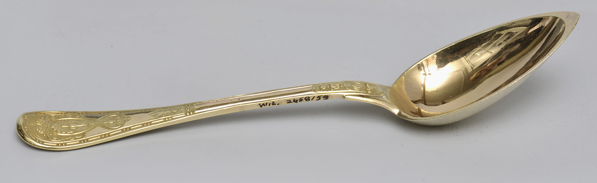 ujęcie 3/4 - widoczna wewnętrzna strona czerpaka. Ujęcie z nabierakiem po prawej stronie i napisem inwentarzowym na bocznej krawędzi rączki.