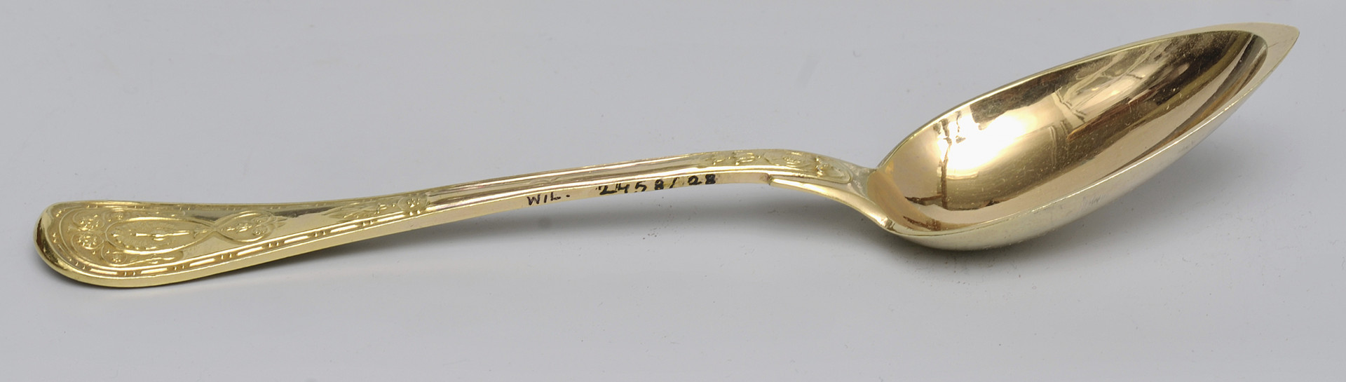 ujęcie 3/4 - widoczna wewnętrzna strona czerpaka. Ujęcie z nabierakiem po prawej stronie i napisem inwentarzowym na bocznej krawędzi rączki.