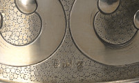puchar weselny - detal; punca znak w tylnej części pucharu, u dołu	 z lewej wystylizowana szyszka pinii , obok z prawej kwadratowe pole z liczbą, z prawej lew kroczący w lewo w pionowym prostokątnym polu