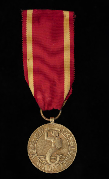 Medal za Warszawę 1939-1945 - ujęcie z przodu; Okrągły krążek, na którego awersie w środku wytłoczony jest wizerunek syreny z tarczą i mieczem (z herbu Warszawy), w dolnej części zaś trzy fale. Wizerunek Syreny otoczony jest pierścieniem, na którym w dolnej części umieszczony jest napis: ZA WARSZAWĘ, a w górnej części oddzielonej od dolnej zniczami umieszczone są daty: 1939 – 1945, pomiędzy którymi znajduje się miecz Syreny. Medal posiada czerwoną wstążkę z żółtymi paskami po bokach.