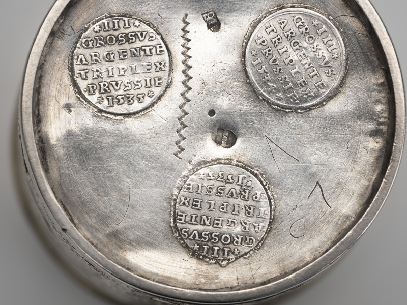 kubek monetowy - detal;  W dno kubka wprawione trzy trójgrosze króla Zygmunta I Starego - od zewnątrz widoczne rewersy z nominałem i rokiem wybicia.