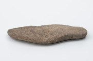 ciężarek do sieci - Ujęcie z boku; Wykonany z piaskowca ciężarek o formie spłaszczonego owalu.