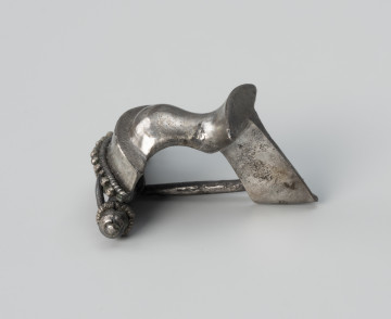 Zapinka ze srebra - ujęcie z prawej; Srebrna fibula z grzebykiem nad sprężynką zdobionym filigranem.
