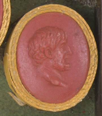 czerwona owalna gemma w grubym złotym obramowaniu; prawy profil mężczyzny w średnim wieku, z krótkimi włosami i brodą, bez wąsów