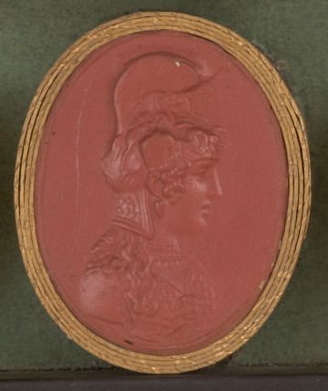 czerwona owalna gemma w grubym złotym obramowaniu; popiersie kobiety widoczne z prawej strony; kobieta jest ubrana w zbroję, ma bogato dekorowany hełm m.in. w pegazy i sfinksy, spod hełmu wychodzą długie kręcone włosy, które opadają na ramiona; na napierśniku zbroi widoczna maska Gorgony; z tyłu za przedstawieniem ledwie widoczna sygnatura: ACIIACIOIV (ASPAZJOS)
