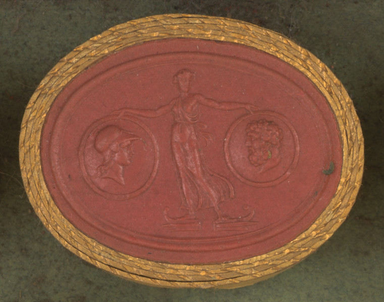 czerwona owalna gemma w grubym złotym obramowaniu; młoda kobieta (Wiktoria) ubrana w cienką, przezroczystą szatę, z odsłoniętą jedną piersią, widziana na wprost; stoi boso na dziobach dwóch okrętów, trzymając w dłoniach dwie okrągłe tarcze: po lewej stronie tarczę z profilem Minerwy w hełmie, po prawej tarczę z z głową Herkulesa, który ma krótkie kręcone włosy, wąsy i brodę.