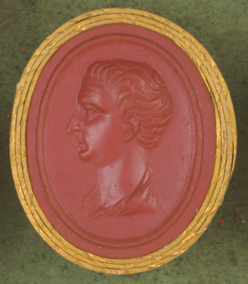 czerwona owalna gemma w grubym złotym obramowaniu; lewy profil mężczyzny w średnim wieku, z krótkimi włosami,długim, prostym nosie i zaokrąglonymi policzkami, poniżej widoczny fragment szaty