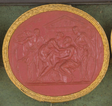 czerwona owalna gemma w grubym złotym obramowaniu; scena przedstawia 6 osób ubranych w stroje antyczne; na pierwszym planie siedzi oślepiony starszy mężczyzna (Edyp), w którego stronę pochyla się młoda kobieta (Antygona); za Edypem stoi młoda kobieta (Ismena). Z lewej strony widoczny jest młody mężczyzna trzymający konia za uzdę. Na dalszym planie widać dwóch kapłanów, a w tle fasadę świątyni