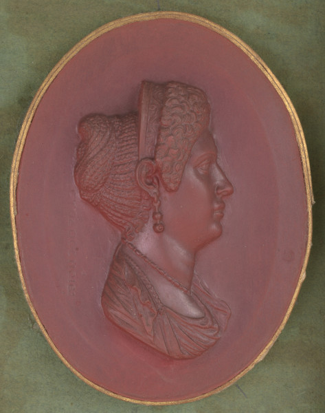 czerwony wycisk owalny ze złotym obramowaniem; prawy profil popiersia Julii Titi, kobieta ma na głowie diadem, a w uszach kolczyki; włosy z tyłu spięte w kok zrobiony z warkoczyków, a na przodzie ułożone w tzw. 