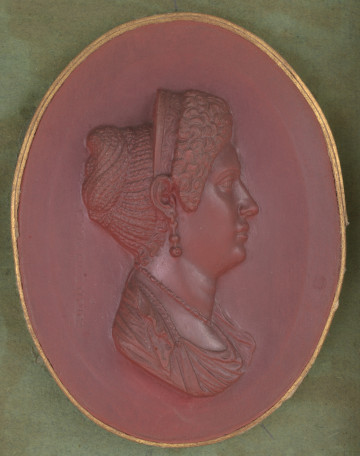 czerwony wycisk owalny ze złotym obramowaniem; prawy profil popiersia Julii Titi, kobieta ma na głowie diadem, a w uszach kolczyki; włosy z tyłu spięte w kok zrobiony z warkoczyków, a na przodzie ułożone w tzw. 