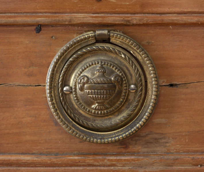 Biurko przyścienne na sześciu nóżkach graniastych zbieżnych. W części dolnej prostokątny prześwit zamknięty tylną ścianą. Po jego bokach po dwie szuflady, powyżej jeszcze trzy. Część górna ćwierćcylindryczna zamykana żaluzją chowaną pod górna płytą powyżej pięciu szufladek, boki zdobione plastycznym ornamentem cekinowym. Lico pokryte fornirem z intarsją ramkową i wzorem arkadkowym. Blat wyłożony skórą cielęcą. Uchwyty szuflad zewnętrznych i żaluzji to nałożone okucia okrągłe z tarczą, szufladki w części górnej mają uchwyty okrągłe z gładką główką.  