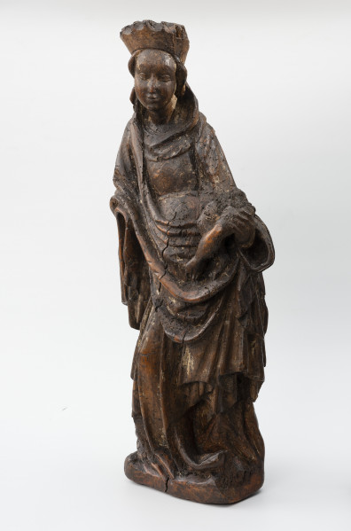 Piękna Madonna z Żarnowa - Ujęcie ze skosu z prawej; figura ołtarzowa; Kobieca figura stojąca na czworobocznej podstawie w obszernych szatach i koronie, trzymająca przy boku dzieciątko. Sylwetka kobieca zakomponowana w wyraźnym kontrapoście, odchylająca tors do tyłu i w lewo, z twarzą zwróconą w trzech czwartych w prawo ku dzieciątku trzymanym na lewym biodrze. Maria ukazana w wieku młodzieńczym nosi długą suknię i płaszcz, którego poła przerzucona przodem układa się w miękką kolistą, wydatną fałdę. Brzegi płaszcza opadają poniżej uniesionych do przodu dłoni spiętrzonymi dekoracyjnie fałdowaniami. Na głowie nałożona wysoka korona oraz chusta zsuwająca się do tyłu i opadająca miękkimi łukami wokół szyi. Twarz owalna z wysokim czołem i wydatnymi policzkami, o łagodnym wyrazie. Dzieciątko o pulchnych nóżkach siedzi przy biodrze, podtrzymywane lewą dłonią matki. Brakuje prawej dłoni Marii i figury dzieciątka powyżej bioder. Na powierzchni rzeźby widoczne pozostałości polichromii.