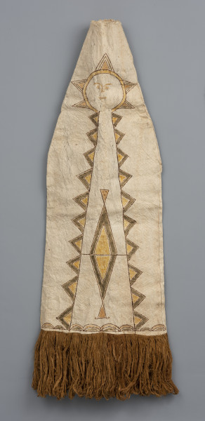 maska do tańca wiatru - Ujęcie z tyłu; Maska (strój) z jasnego włókna roślinnego (tapy) o podłużnym, trójkątnym kształcie rozszerzającym się ku dołowi, który wykończono brązowymi frędzlami z włókien roślinnych. Widzimy centralnie rozmieszczony kolorowy rysunek przypominający słońce od którego odchodzą różnego rodzaju pasy wzorów geometrycznych: proste i zakręcone linie, zygzaki, romby, trójkąty, półkola. Namalowane słońce wydają się być głową, która ma zaznaczone symboliczne rysy twarzy: oczy z rzęsami, nos, brwi i usta. Od główy odchodzą kolorowe trójkąty (żółto-brązowo-zielone lub żółto-brązowe), kojarzące się z promieniami oraz długie pasma wzorów geometrycznych, ułożone tak, że przypominają ciało. Postać wyróżnia usytuowany centralnie wzór brązowo-zielono-żółtego rombu i dwóch żółto-brązowych trójkątów. Rysunek zakończony jest wzorem wykorzystującym półkola. Obiekt uszkodzony w wielu miejscach. Ma liczne przerwania i przebarwienia.