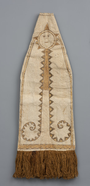 maska do tańca wiatru - Ujęcie z przodu; Maska (strój) z jasnego włókna roślinnego (tapy) o podłużnym, trójkątnym kształcie rozszerzającym się ku dołowi, który wykończono brązowymi frędzlami z włókien roślinnych. Widzimy centralnie rozmieszczony kolorowy rysunek przypominające słońce od którego odchodzą różnego rodzaju pasy wzorów geometrycznych: proste i zakręcone linie, zygzaki, romby, trójkąty, półkola. Namalowane słońce wydają się być głową, która ma zaznaczone symboliczne rysy twarzy: oczy z rzęsami, nos, brwi i usta. Od główy odchodzą kolorowe trójkąty (żółto-brązowo-zielone lub żółto-brązowe), kojarzące się z promieniami oraz długie pasma wzorów geometrycznych, ułożone tak, że przypominają ciało. Postać (z żółto-brązowymi promieniami) ma również namalowane uszy oraz podwójne linie puszczone przy bocznych krawędziach. Jej centralny wzór geometryczny w postaci zakręcających spiralnie linii z kolorowymi zygzakami wypełniony jest do połowy żółtym barwnikiem. Rysunek zakończony jest wzorem wykorzystującym półkola. Obiekt uszkodzony w wielu miejscach. Ma liczne przerwania i przebarwienia.