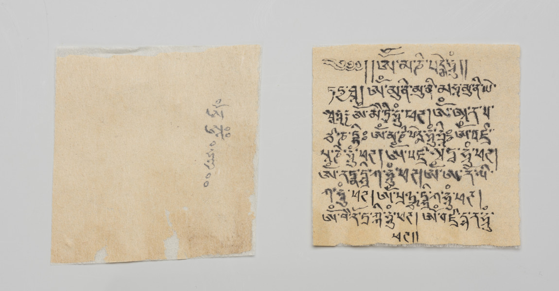 figurka Bodhisattwa Awalokiteśwara Padmapani wraz z wypełnieniem - ujęcie z przodu; Dwa kawałki papieru zapisane mantrami i tekstem konsekracyjnym, najprawdopodobniej są to trzy sylaby reprezentujące żywego Buddę, energię, umysł i przestrzeń.