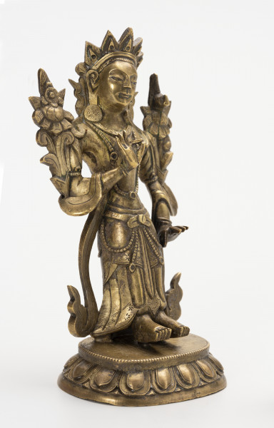 figurka Bodhisattwa Awalokiteśwara Padmapani wraz z wypełnieniem - ujęcie ze skosu z lewej; Mała, wykonana z brązu figurka przedstawiająca Bodhisattwę Awalokiteśwarę Padmapani Postać ludzka o skupionej, lekko uśmiechniętej twarzy. Stoi na lotosowym postumencie o 11 parach odwróconych płatków, którego górną część ozdobiono paciorkami. Ubrana jest w szaty królewskie: przewiązaną w talii tkaninę z paskiem od którego odchodzą łańcuszki z paciorków oraz biżuterię książęcą: trójramienny diadem, parę, dużych, okrągłych kolczyków, podwójny naszyjnik z paciorków z wisiorkami, bransolety na nadgarstkach i przedramionach. Do prawego ramienia przylega kwiat lotosu (typowy atrybut), natomiast po lewej stronie, symetrycznie, na tej samej wysokości, przylega przypominający kwiat lotosu niezidentyfikowany atrybut Awalokiteśwary. Obie dłonie ułożone są w geście argumentacji: kciuk i palec wskazujący złączone, tworzą krąg. Prawa uniesiona jest na wysokości klatki piersiowej, lewa opada wzdłuż ciała, zatrzymując się na wysokości biodra. Z ramion figurki zwisa przewieszona skóra antylopy.