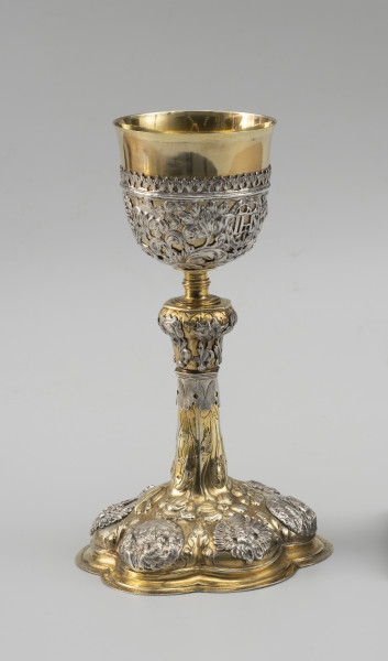 kielich mszalny - Ujęcie z przodu; Smukły kielich o sześciolistnej, wysklepionej stopie, przechodzącej w sześcioboczną, zwężającą się ku górze wysoką tuleję. Nodus sześcioboczny, wybrzuszony w górnej części, oddzielony tralkowym trzonem od czary ujętej do wysokości 2/3 ażurowym koszyczkiem.

Pola stopy zdobione naprzemiennie srebrnymi reliefowymi nakładkami z uskrzydlonymi główkami anielskimi oraz owalnymi plakietkami ze scenami Narodzin Chrystusa, Hołdu Trzech Króli i Ostatniej Wieczerzy. Wyższe partie stopy oraz tuleję pokrywa repusowany i rytowany wzór z naturalistycznych kwiatów na długich ulistnionych łodygach, zwróconych główkami w dół. Dekorację nodusa tworzy sześć wycinanych w srebrnej blasze i repusowanych srebrnych nakładek w formie pojedynczych kwiatów (tulipanów i irysa). Motywy kwiatowe w połączeniu z wicią akantową występują również w dekoracji koszyczka. Pomiędzy nie wkomponowano trzy owalne kartusze otoczone wieńcami laurowymi z hierogramami Chrystusa, Marii oraz św. Józefa.