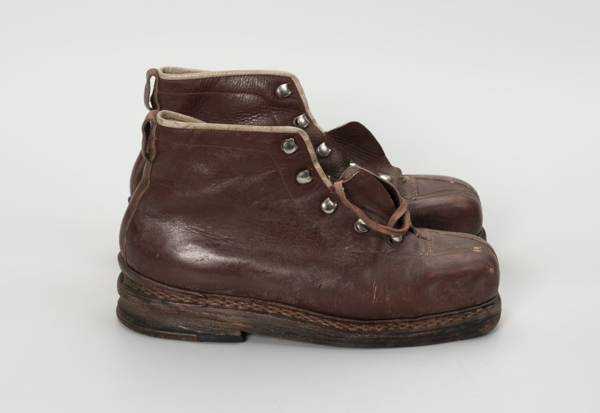 para trzewików - Ujęcie prawy bok; Para damskich, brązowych, sznurowanych butów. Otwory na sznurówki zabezpieczone metalowymi obwódkami. Cholewka wykonana ze skóry licowej bydlęcej. To naturalna skóra, której zewnętrzna warstwa została poddana obróbce mechanicznej powodującej jej gładką fakturę. Buty noszą ślady dużej eksploatacji, uszkodzenia skóry przy górnym zakończeniu buta oraz po całości widoczna popękana skóra.