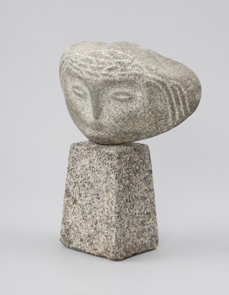 rzeźba; głowa - Ujęcie ze skosu z prawej; Szeroka, spłaszczona, bliska owoidalnej głowa dołem lekko wydłużona, osadzona na kostce w kształcie ściętego ostrosłupa. Rysy twarzy: łuki brwiowe, nos, konturowo zaznaczone oczy, drobne usta – ciemniejsze, wydobyte przez delikatny, negatywowy szlif policzków i obszarów wokół oczu. Ryt ornamentalny włosów widoczny tylko na froncie skały, bezpośrednio wokół twarzy.