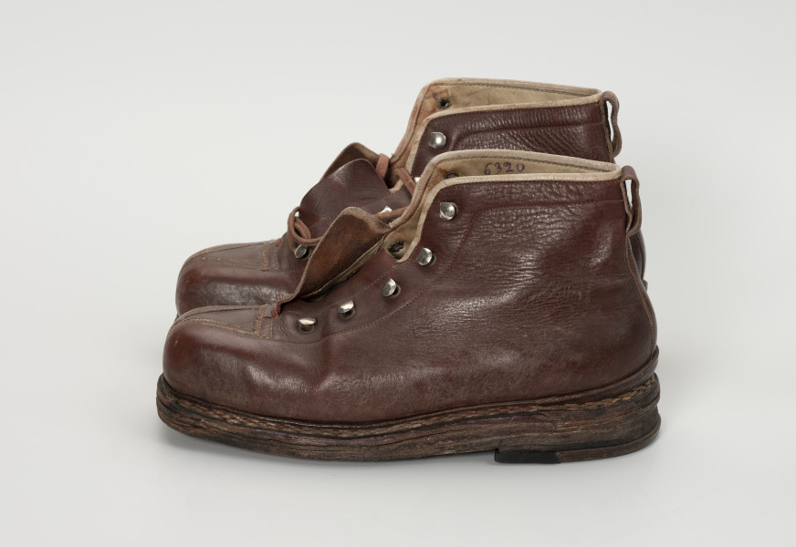 para trzewików - Ujęcie lewy bok; Para damskich, brązowych, sznurowanych butów. Otwory na sznurówki zabezpieczone metalowymi obwódkami. Cholewka wykonana ze skóry licowej bydlęcej. To naturalna skóra, której zewnętrzna warstwa została poddana obróbce mechanicznej powodującej jej gładką fakturę. Buty noszą ślady dużej eksploatacji, uszkodzenia skóry przy górnym zakończeniu buta oraz po całości widoczna popękana skóra.