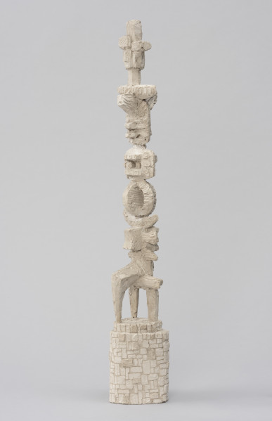 rzeźba; Światowid I - ujęcie tyłu ze skosu z prawej; Smukła, abstrakcyjna forma o jasnoszarej barwie na podstawie. Na szczycie antropomorficzna głowa o czterech twarzach umieszczona na słupie. Poniżej, jedna na drugiej, nieokreślone formy: belkowate; geometryczne, w tym zespolone ze sobą koła ustawione pionowo, pod kątem prostym względem siebie; formy księżycowate; przenikające się krzyżowo z trójnogiem u dołu. Powierzchnia gipsu niejednorodna: miejscami ze śladami szpachli i innych narzędzi, rysami; miejscami zaś opracowana szczegółowiej - wygładzona nieco w środkowej partii o geometrycznej formie z wkomponowanymi w nią dwoma płaskimi dyskami, na bokach których odciśnięto czworoboki z kołami w środku. Dwustopniowa podstawa w formie pionowo ustawionego walca o jajowatym przekroju i dokładnie opracowanej powierzchni, dającej wrażenie kamiennego muru.