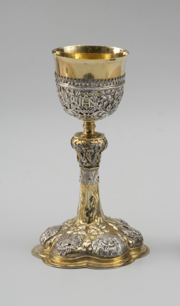kielich mszalny - Ujęcie z przodu; Smukły kielich o sześciolistnej, wysklepionej stopie, przechodzącej w sześcioboczną, zwężającą się ku górze wysoką tuleję. Nodus sześcioboczny, wybrzuszony w górnej części, oddzielony tralkowym trzonem od czary ujętej do wysokości 2/3 ażurowym koszyczkiem.

Pola stopy zdobione naprzemiennie srebrnymi reliefowymi nakładkami z uskrzydlonymi główkami anielskimi oraz owalnymi plakietkami ze scenami Narodzin Chrystusa, Hołdu Trzech Króli i Ostatniej Wieczerzy. Wyższe partie stopy oraz tuleję pokrywa repusowany i rytowany wzór z naturalistycznych kwiatów na długich ulistnionych łodygach, zwróconych główkami w dół. Dekorację nodusa tworzy sześć wycinanych w srebrnej blasze i repusowanych srebrnych nakładek w formie pojedynczych kwiatów (tulipanów i irysa). Motywy kwiatowe w połączeniu z wicią akantową występują również w dekoracji koszyczka. Pomiędzy nie wkomponowano trzy owalne kartusze otoczone wieńcami laurowymi z hierogramami Chrystusa, Marii oraz św. Józefa.