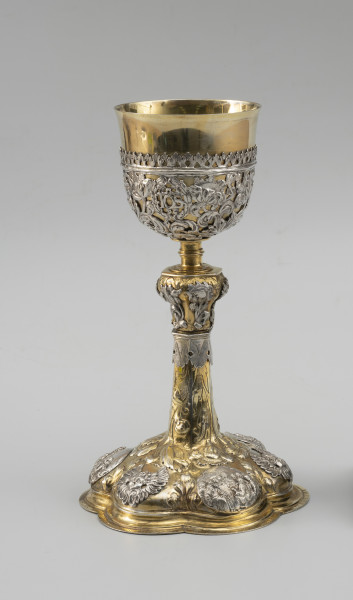 kielich mszalny - Ujęcie z przodu; Smukły kielich o sześciolistnej, wysklepionej stopie, przechodzącej w sześcioboczną, zwężającą się ku górze wysoką tuleję. Nodus sześcioboczny, wybrzuszony w górnej części, oddzielony tralkowym trzonem od czary ujętej do wysokości 2/3 ażurowym koszyczkiem.

Pola stopy zdobione naprzemiennie srebrnymi reliefowymi nakładkami z uskrzydlonymi główkami anielskimi oraz owalnymi plakietkami ze scenami Narodzin Chrystusa, Hołdu Trzech Króli i Ostatniej Wieczerzy. Wyższe partie stopy oraz tuleję pokrywa repusowany i rytowany wzór z naturalistycznych kwiatów na długich ulistnionych łodygach, zwróconych główkami w dół. Dekorację nodusa tworzy sześć wycinanych w srebrnej blasze i repusowanych srebrnych nakładek w formie pojedynczych kwiatów (tulipanów i irysa). Motywy kwiatowe w połączeniu z wicią akantową występują również w dekoracji koszyczka. Pomiędzy nie wkomponowano trzy owalne kartusze otoczone wieńcami laurowymi z hierogramami Chrystusa, Marii oraz św. Józefa.