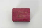 pudełko jubilerskie - Ujęcie z góry; Małe, prostopadłościenne pudełko na biżuterię, z twardej tektury w kolorze amarantowym, delikatnie prążkowane. Pudełeczko otwierane uchylnie. Na wieczku napis czcionką w kolorze złotym: Rud. Kunstmann Juwelier Stettin Paradeplatz 12.