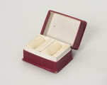 pudełko jubilerskie - Ujęcie przodu ze skosu z prawej; Małe, prostopadłościenne pudełko na biżuterię, z twardej tektury w kolorze amarantowym. Pudełeczko otwierane uchylnie – na widocznym zdjęciu otwarte.