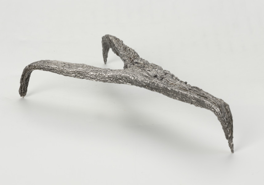 rak żelazny - Ujęcie tyłu ze skosu z lewej; Rak żelazny trójramienny z czworobocznej sztabki żelaznej z haczykiem na końcu każdego ramienia.