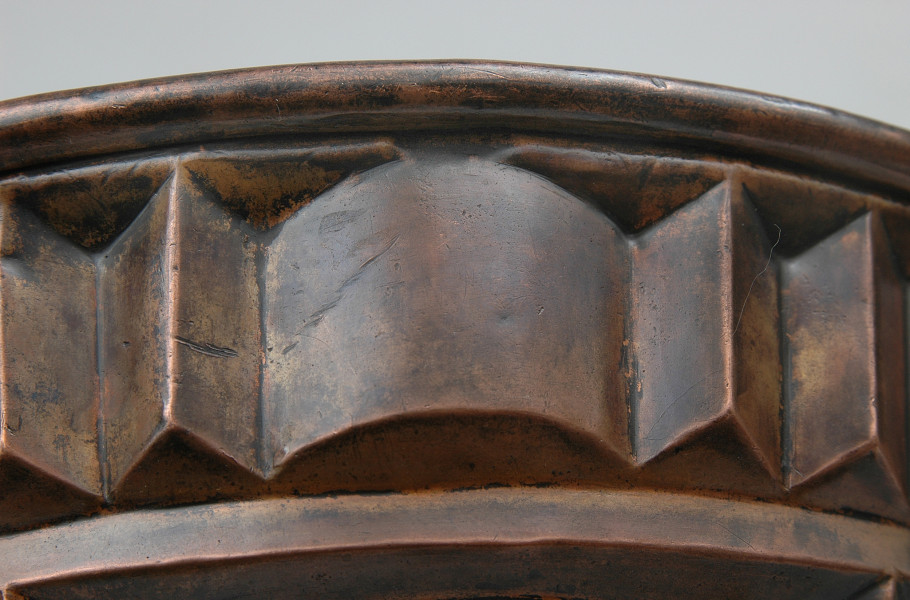 zbliżenie na dolną partię dekoracji. Pas złożony z powtarzalnych elementów: półwałka i trzech ostrosłupów.