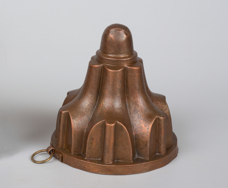 ujęcie 3/4. Stożkowate naczynie z sześcioma powtarzającymi się kształtkami i kulką na szczycie.