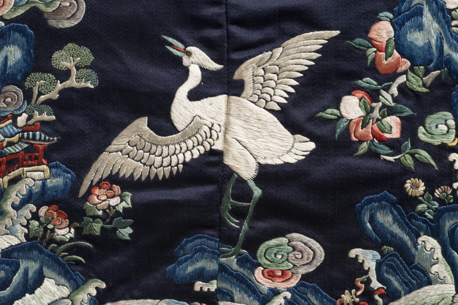 Na jedwabiu wyhaftowany żuraw z rozpostartymi skrzydłami.
