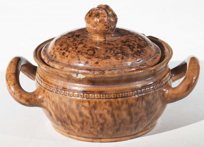 Miseczka okrągła z dwoma uchwytami i pokrywką. Pokrywka zakończona uchwytem w kształcie pąka kwiatu. Całość w kolorze wypalonej gliny