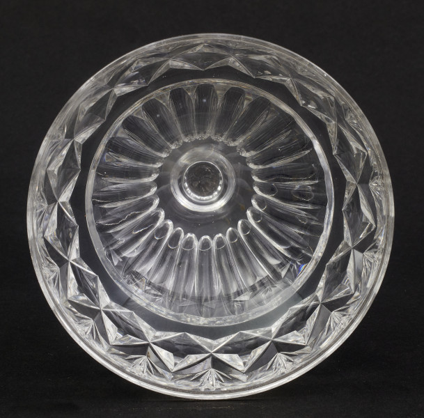 Stopa okrągła, nóżka krótka i szeroka, zakończona pierścieniem, na którym osadzona stożkowata czara. Spód stopy dekorowany płytkim szlifem o motywie wielopłatkowego kwiatka.