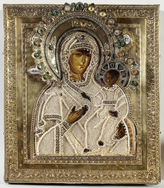 ikona z wizerunkiem Bogurodzicy Hodigitrii Smoleńskiej w półpostaci; Dzieciątko siedzi po prawej stronie, prawicą błogosławi, w lewicy trzyma zwinięty zwój; w krzyżowym nimbie Chrystusa monogram ωTOH; w tle inskrypcje cyrylickie opisujące postacie: IC XC;  МР ΘУ |  ОДИГІТРИЯ; na lico nałożony okład i aplikacja