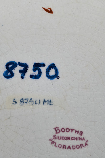 Stołowy, płytki talerzyk wykonany z białego fajansu. Zdobiony wielobarwną kalkomanią, złożoną z czterech jednakowych asymetrycznych roślinnych kompozycji